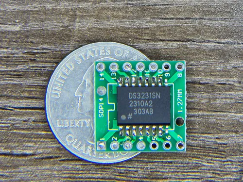 DS3231 RTC chip on a SOP14 adapter board next to a quarter for scale