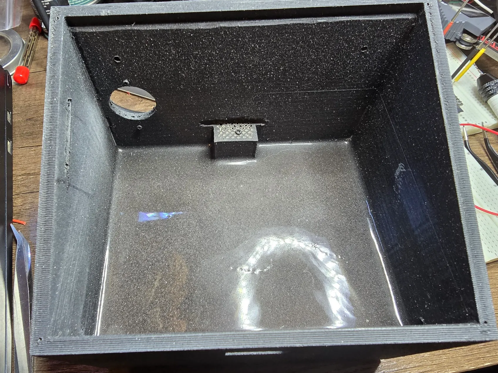 Inside of the printed enclosure, with steel shot set in a glossy pour of epoxy across the floor