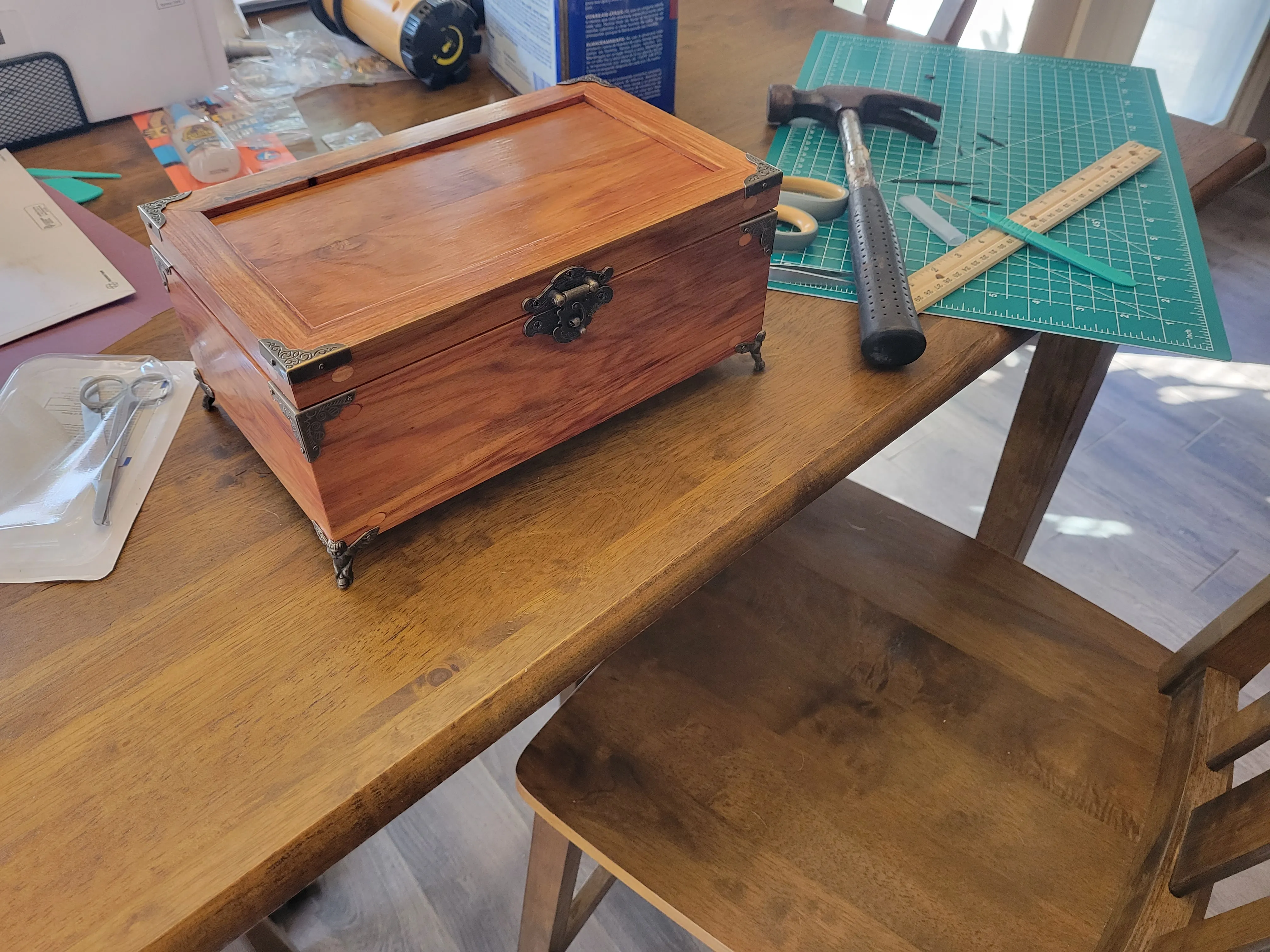 Finished canarywood box with brass corner hardware, ball feet, and a swing clasp