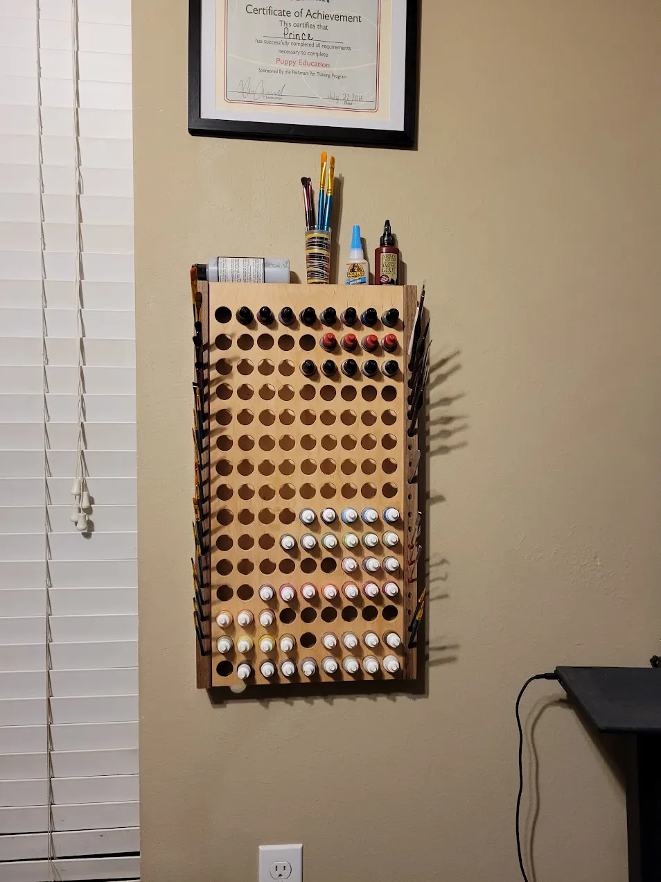 Finished wall-mounted paint rack loaded with paint bottles and brushes