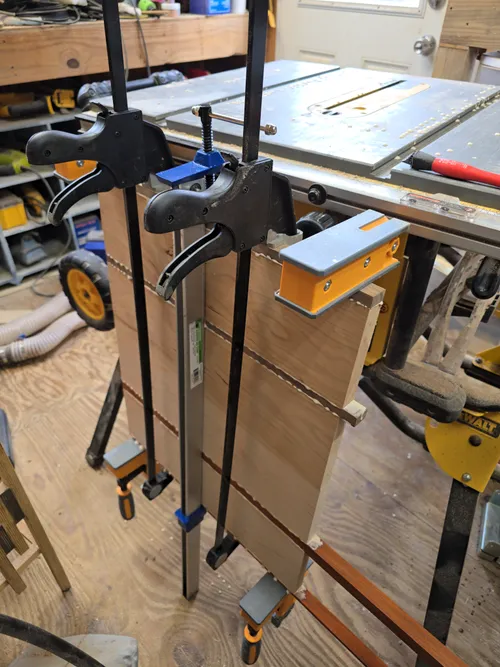 A board blank clamped up with bar clamps during glue-up
