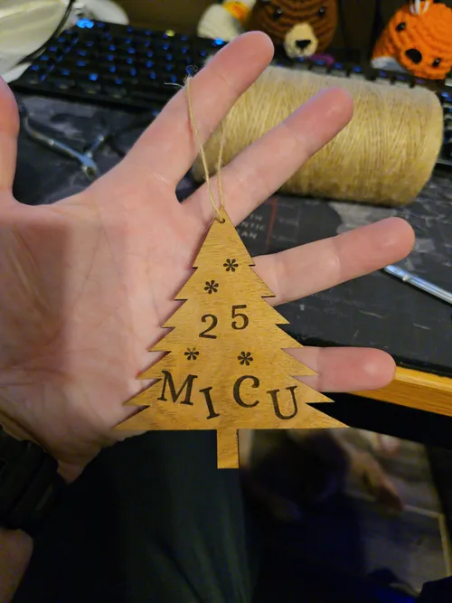 Laser-engraved wood Christmas tree ornament reading MICU 25 with snowflake accents