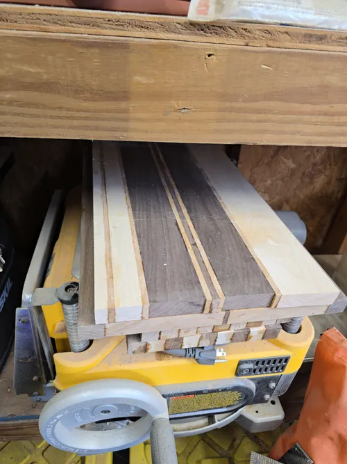 A glued-up striped blank sitting on top of a benchtop planer